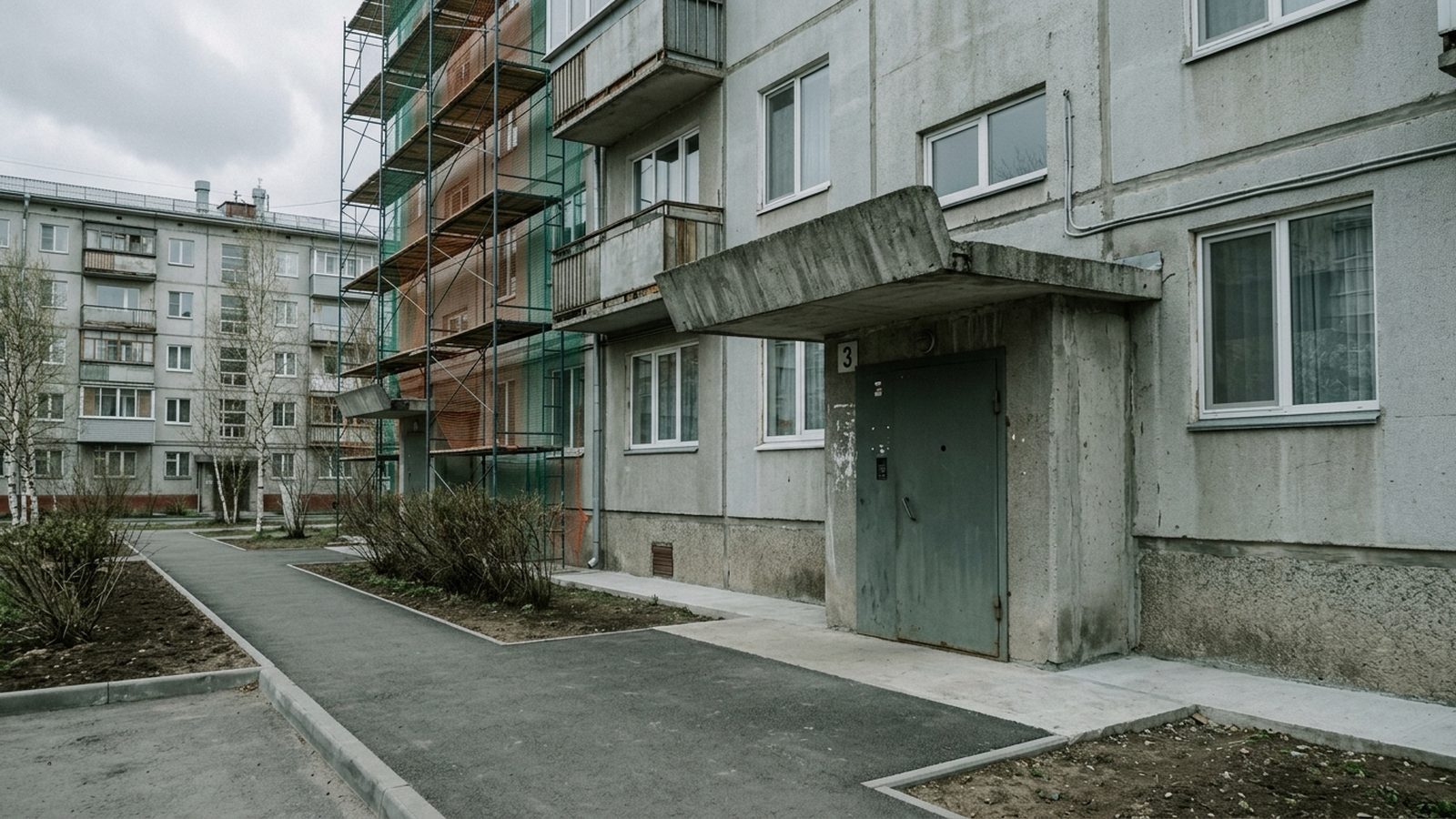 Вход в подъезд многоквартирного дома, часть фасада в строительных лесах